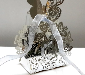 Close-up of laser-cut butterfly wedding favor box with silver ribbon handle