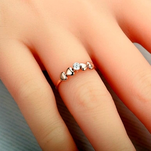 Close-up of rose gold titanium ring with round zircon and heart design on finger