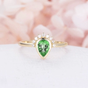 Macro shot of a teardrop green gemstone crown ring with white diamonds on pink petals