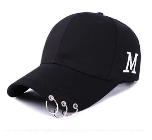 Détail de la casquette noire avec anneaux métalliques sur la visière et broderie lettre M