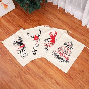 Detail of four linen Christmas drawstring gift bags with reindeer prints on wood floor