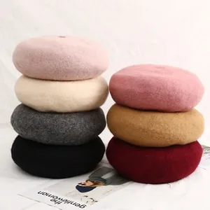 Detailed stack of multi-colored wool berets in pink, beige, and red for autumn winter