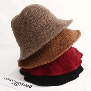 Detail of multi-color cable-knit bucket hats stacked vertically in autumn shades