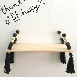 Detail of wooden wall shelf with white ropes, macaron beads and black tassels