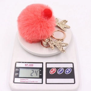 Detailed view of red plush sequined reindeer keychain on a digital scale weighing 24 grams