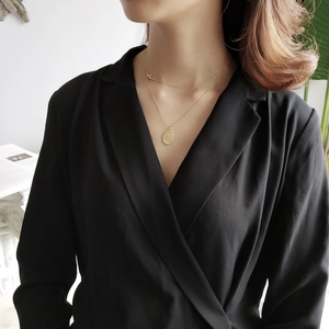 Detailed close-up of a minimalist gold double-layered necklace with a round pendant on a model