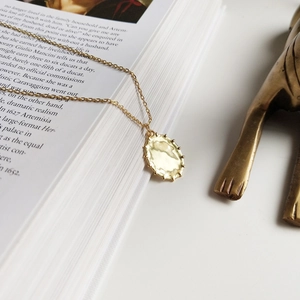 Detailed close-up of a 925 sterling silver gold-plated oval pendant necklace on a vintage book