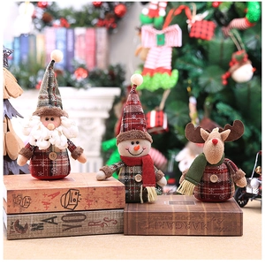 Detailed plush Christmas figurines with plaid fabric hats and scarves on decorative books