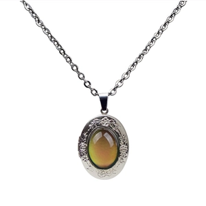Detailed close-up of vintage oval mood stone pendant with engraved floral silver edges