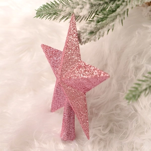 Pink glitter star tree topper on white faux fur background with snowy pine needles décor