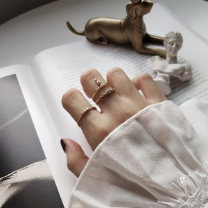 Three-piece set of gold 925 silver rings with zircons stacked on a model's hand