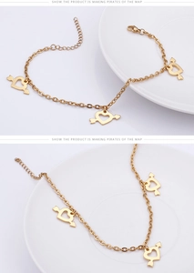 Detailed macro view of gold-plated titanium anklet featuring three heart arrow charms
