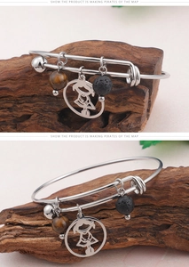 Détail d'un bracelet réglable en acier avec oeil de tigre, pierre de lave et pendentif fille