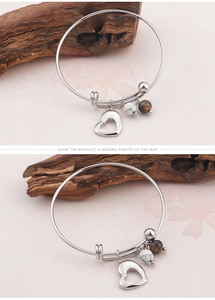 Détail du bracelet avec breloque cœur et perles marbrées sur support en bois