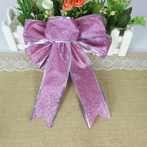 Detailed view of pink glitter Christmas bow with silver trim on rustic burlap background