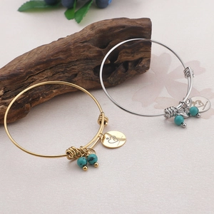 Minimalist gold and silver bracelets with turquoise beads and heart pendant on wood