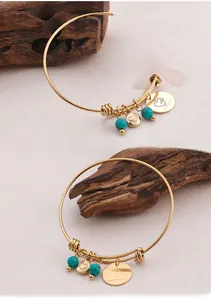 Detail of gold bangle featuring Happy Mother's Day engraved heart and turquoise beads