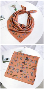 Detail of rust orange silk scarf featuring cartoon zebra and blue heart patterns