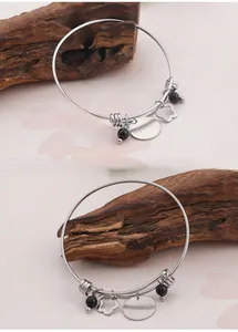Close-up of silver open bangle featuring heart pendants and I Love You Mom engraving