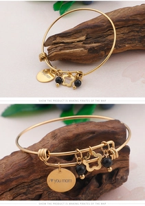 Detail of MOM love you gold bracelet with engraved heart charm and floral pendant