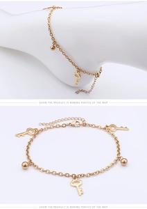 Detail of golden anklet featuring small key charms and round beads on a minimalist chain