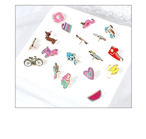 Flat lay of diverse colorful enamel pins featuring flamingo, mermaid, and heart designs