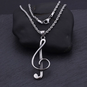 Polished silver treble clef musical note pendant necklace on a dark textured stone