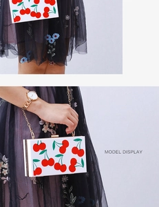 White acrylic square clutch bag with red cherry print and gold chain strap detail