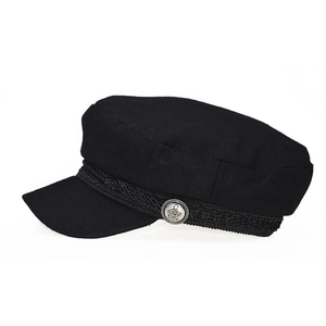Detail of black wool newsboy hat featuring braided strap and silver crown button