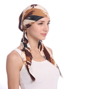 Detailed view of women's turban hat with artistic brown and black graffiti print texture