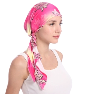 Detail showing the elegant drape and floral print of the pink headscarf on a model