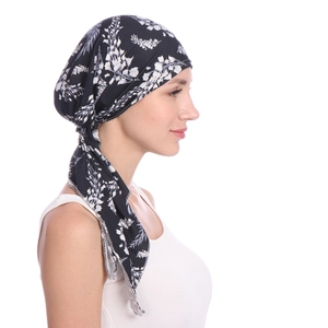 Detail view of women's soft black headscarf with white floral patterns on model's profile