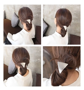 Detail view of a silver geometric triangle metal hair clip worn on a bun hairstyle