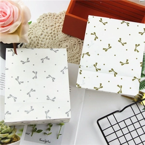 Detail view of gold and silver bow pattern paper gift bags with elegant floral background
