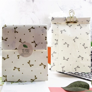 Detail of white translucent paper gift bags with gold and silver bow prints and clips