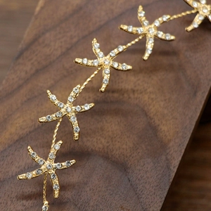 Elegant gold starfish headband for weddings with sparkling rhinestones on a wooden surface