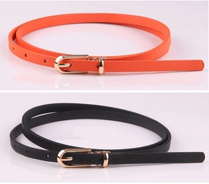 Close-up of black and orange slim faux leather belts with polished gold pin buckles