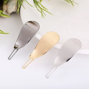 Detailed view of three metal teardrop hair clips in matte grey, gold, and silver finishes