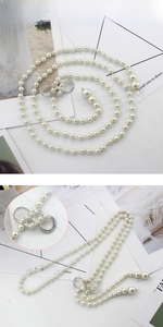 Détail d'une élégante ceinture en perles blanches avec boucle en strass argentés en forme de huit