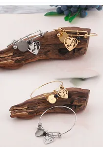 Detail of adjustable gold and silver mother's bracelets with heart charms on wood