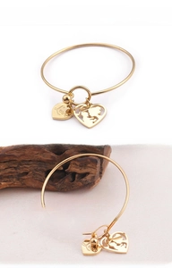 Detail of gold heart charms on a sleek bangle featuring mother and child silhouette