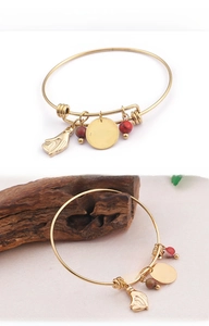 Detail of adjustable gold bangle with heart charm, palm pendant, and colored beads