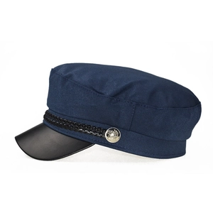 Detail view of navy blue sailor hat with black brim, braided rope and metal button decoration