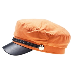 Detail of orange baker boy hat with black leather brim and golden crest button