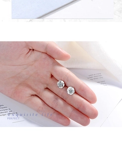 Macro detail of silver rose flower stud earring with sparkling zircon held by hand