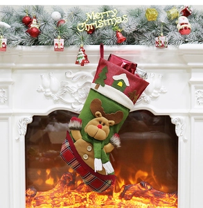 Green Christmas stocking with 3D reindeer decor hanging on a festive decorated fireplace