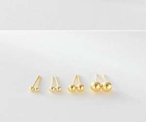 Four pairs of polished gold ball stud earrings in varying sizes on white background