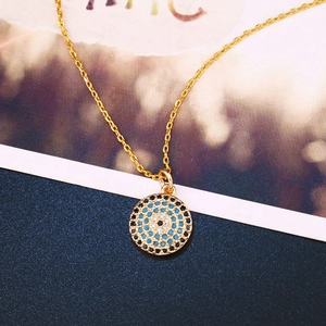 Detail van gouden Evil Eye hanger met blauwe en witte zirkoonstenen aan een ketting