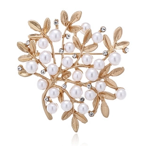 Detail showing golden leaf brooch with embedded white pearls and sparkling rhinestones