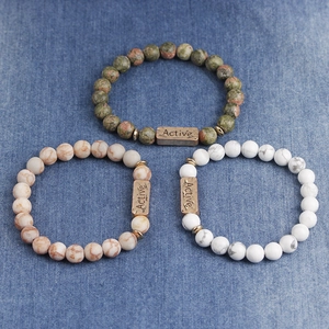 Macro shot of three natural stone beaded bracelets with Active engraved bronze metal beads